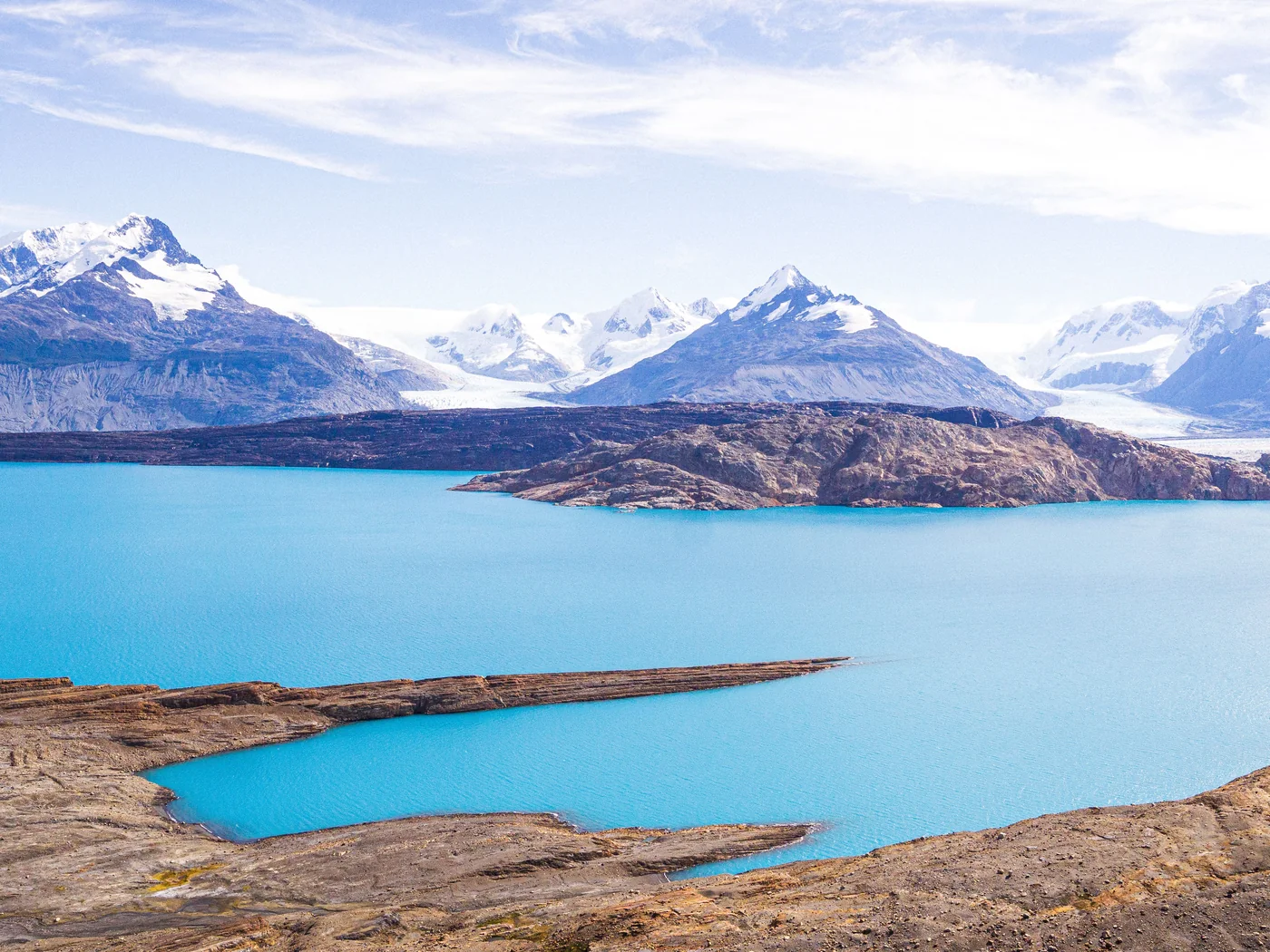 Turquoise glacial lake water with glacier tongues descending from snow-capped mountains